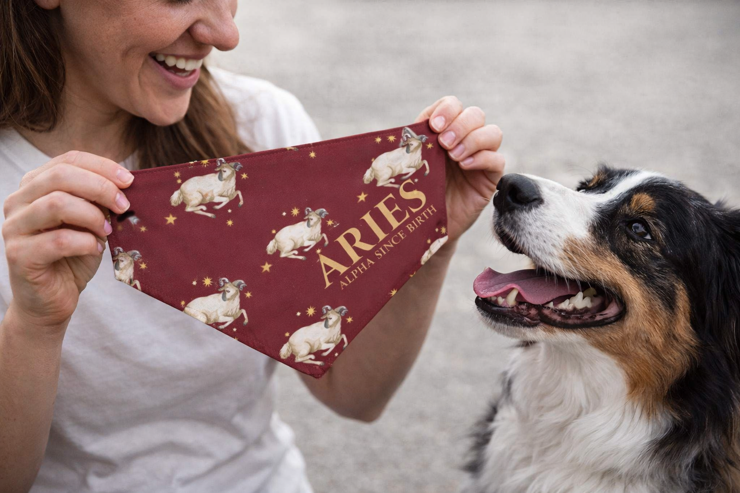 Person holding a red bandana with 'ARIES' and dog illustrations, next to a dog.
